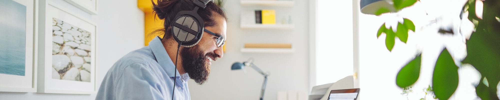 Happy man wearing headphones working on computer